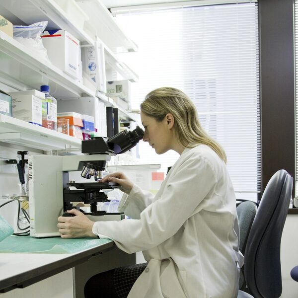 Ricercatrice al microscopio in laboratorio partner